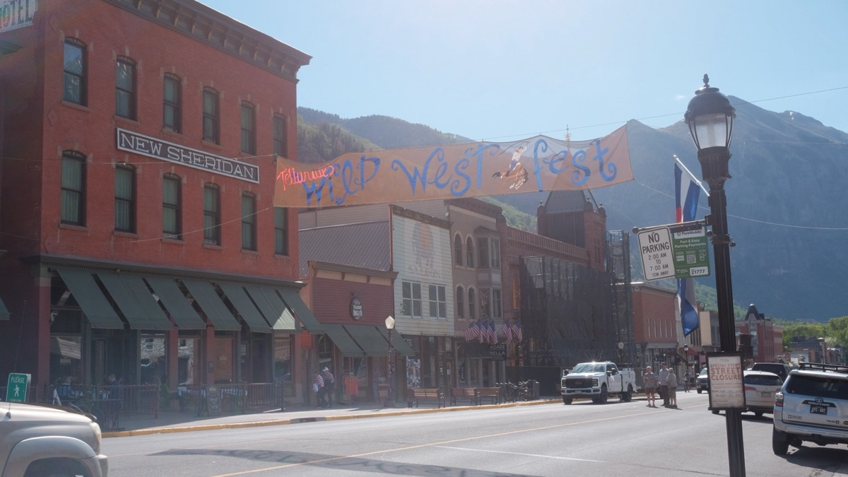 Main street with the brick New Sheridan hotel and a Wild West Fest banner, mountains behind