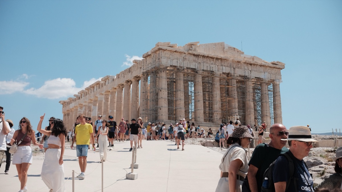 Crowds of visitors in front of the Parthenon under a blue sky